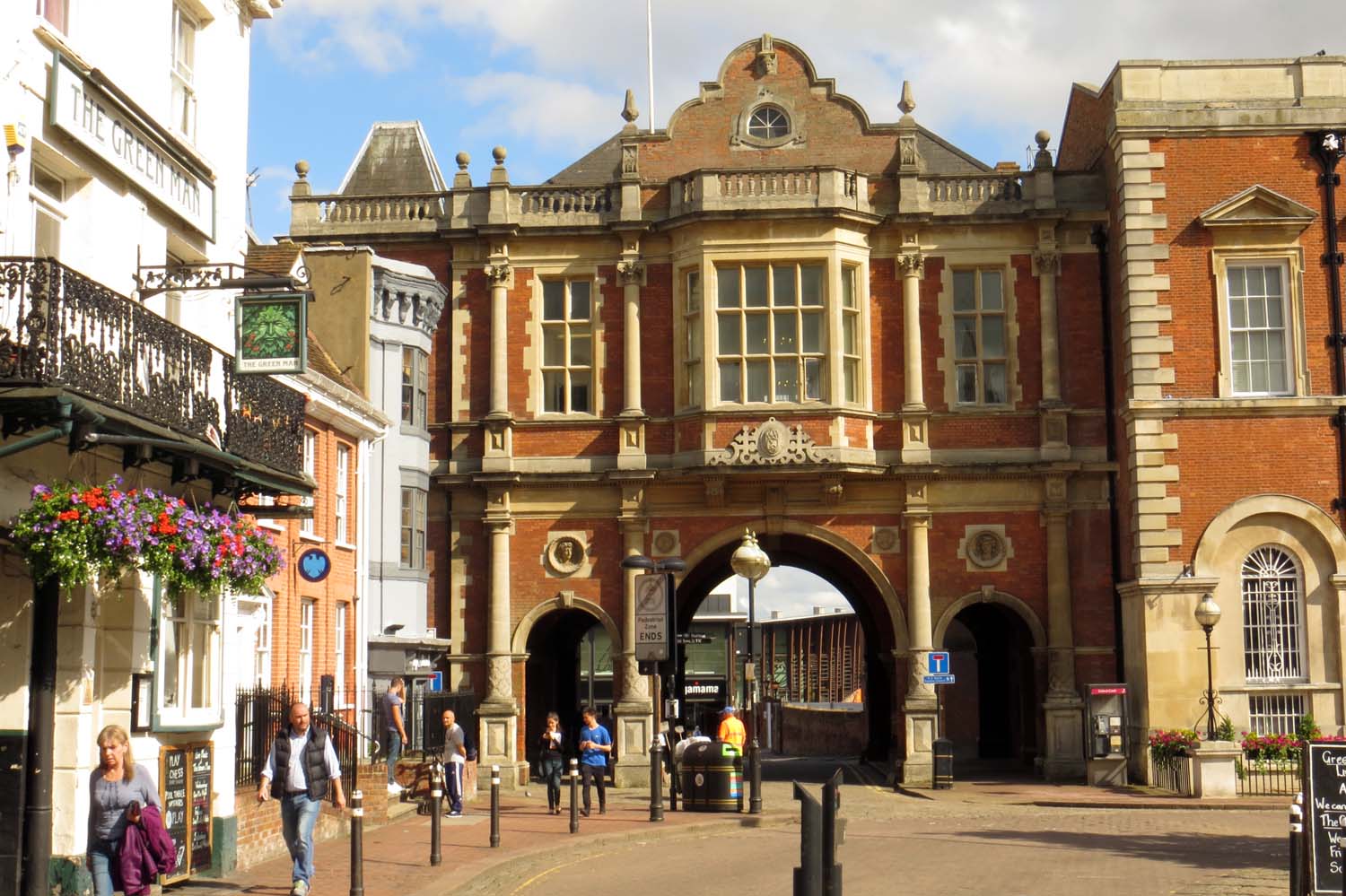 The arched Victorian market building on Aylesbury's Market Square, with people walking underneath it.