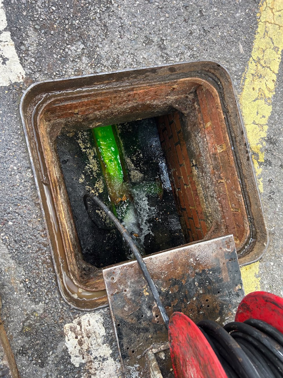 The same chamber jetted clean, with the green pipe now visible and water running through freely.