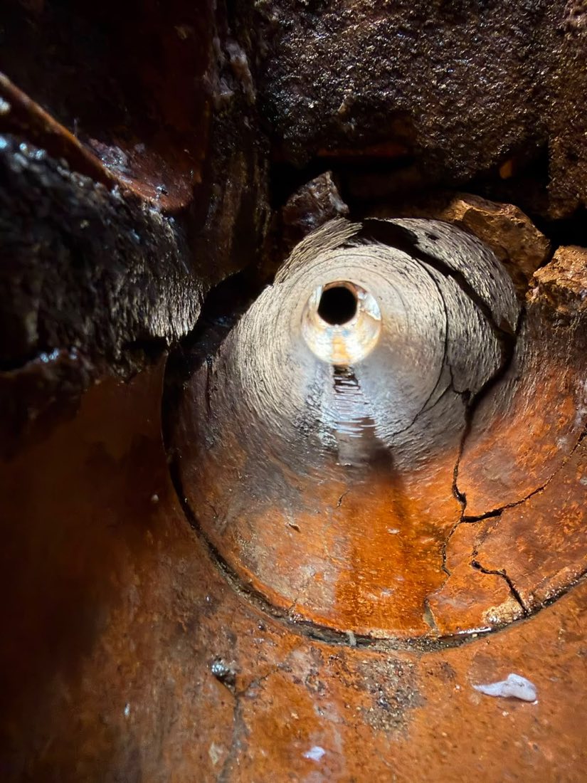 Close-up of a cracked and broken clay drain pipe with a displaced joint.