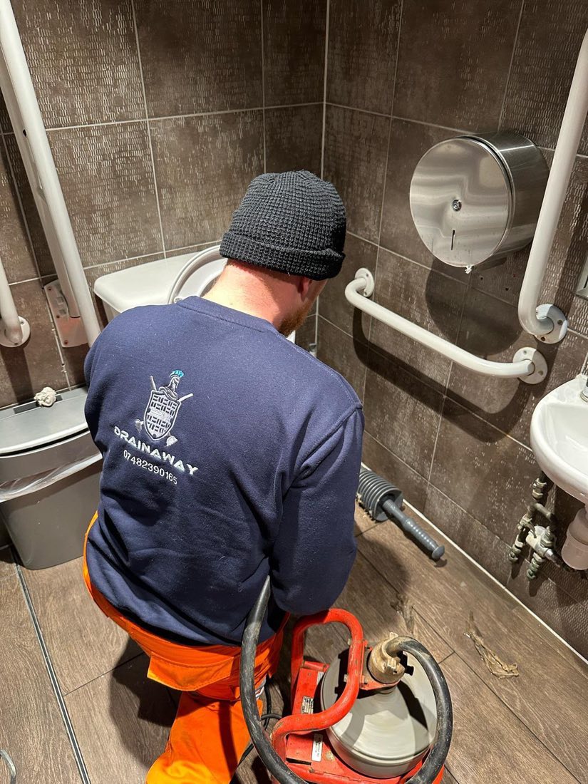 A DrainAway engineer working on a blocked drain in a commercial toilet block.