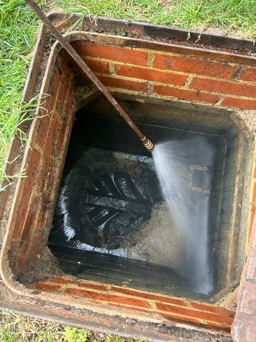 High pressure water jetting inside a brick inspection chamber, with spray coming off the lance.