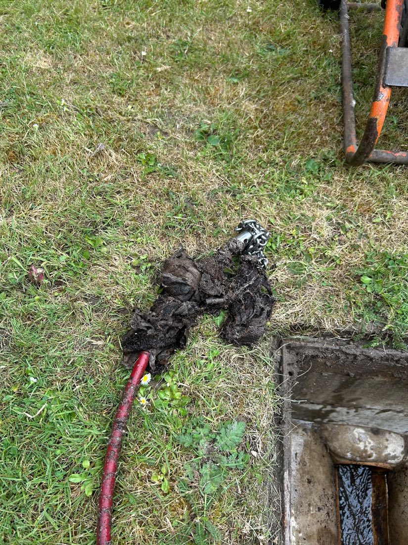 A large mass of wet wipes pulled out of a drain on a jetting hose and laid on the grass.